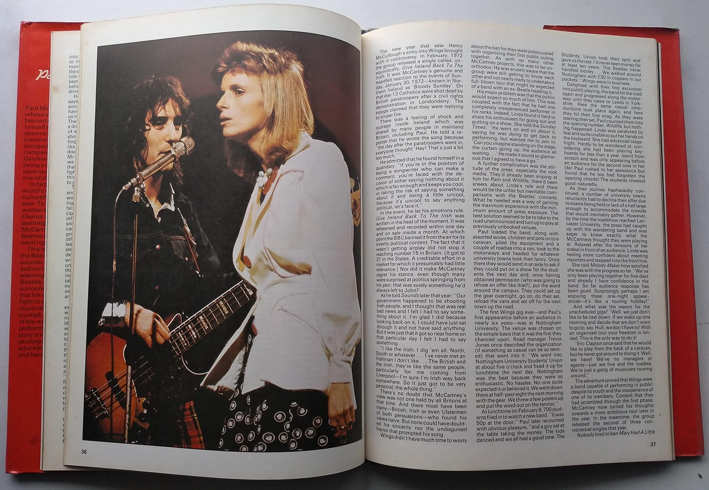 An open book showing a vintage color photograph of a rock band performing on stage on the left page, with dense columns of text on the right page. The book has red side borders.